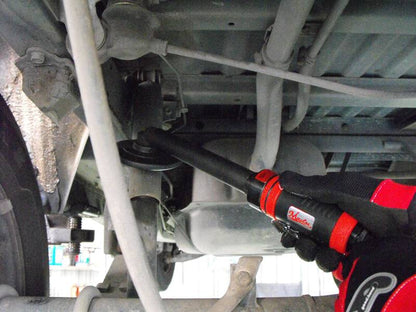 a close up of a person holding a wrench under a vehicle