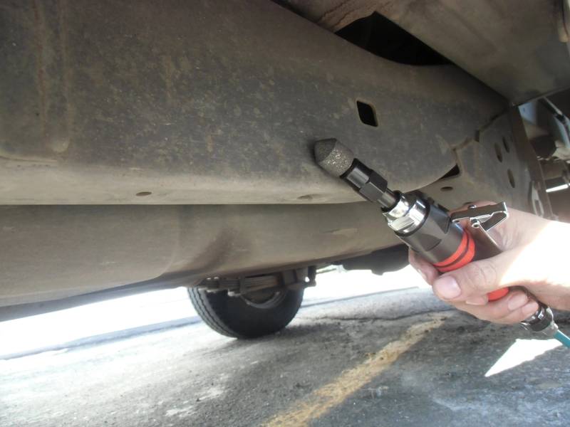 a person holding a wrench under a vehicle