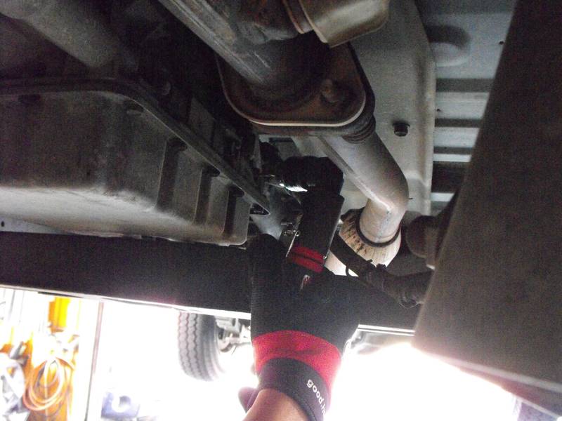 a close up of a person holding a wrench under a vehicle