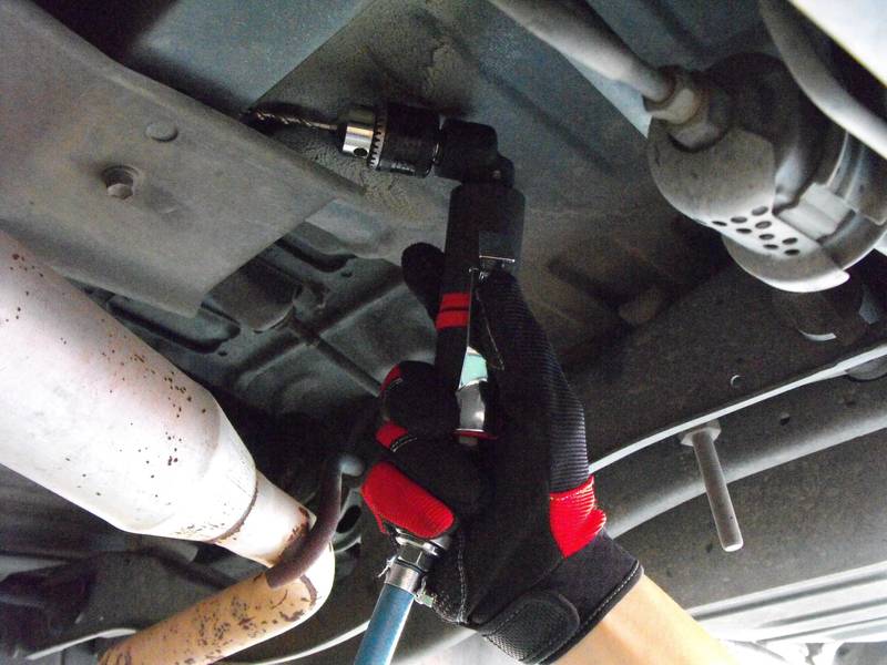 a close up of a person holding a wrench under a vehicle