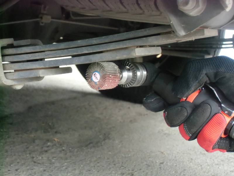 a close up of a person holding a wrench under a vehicle